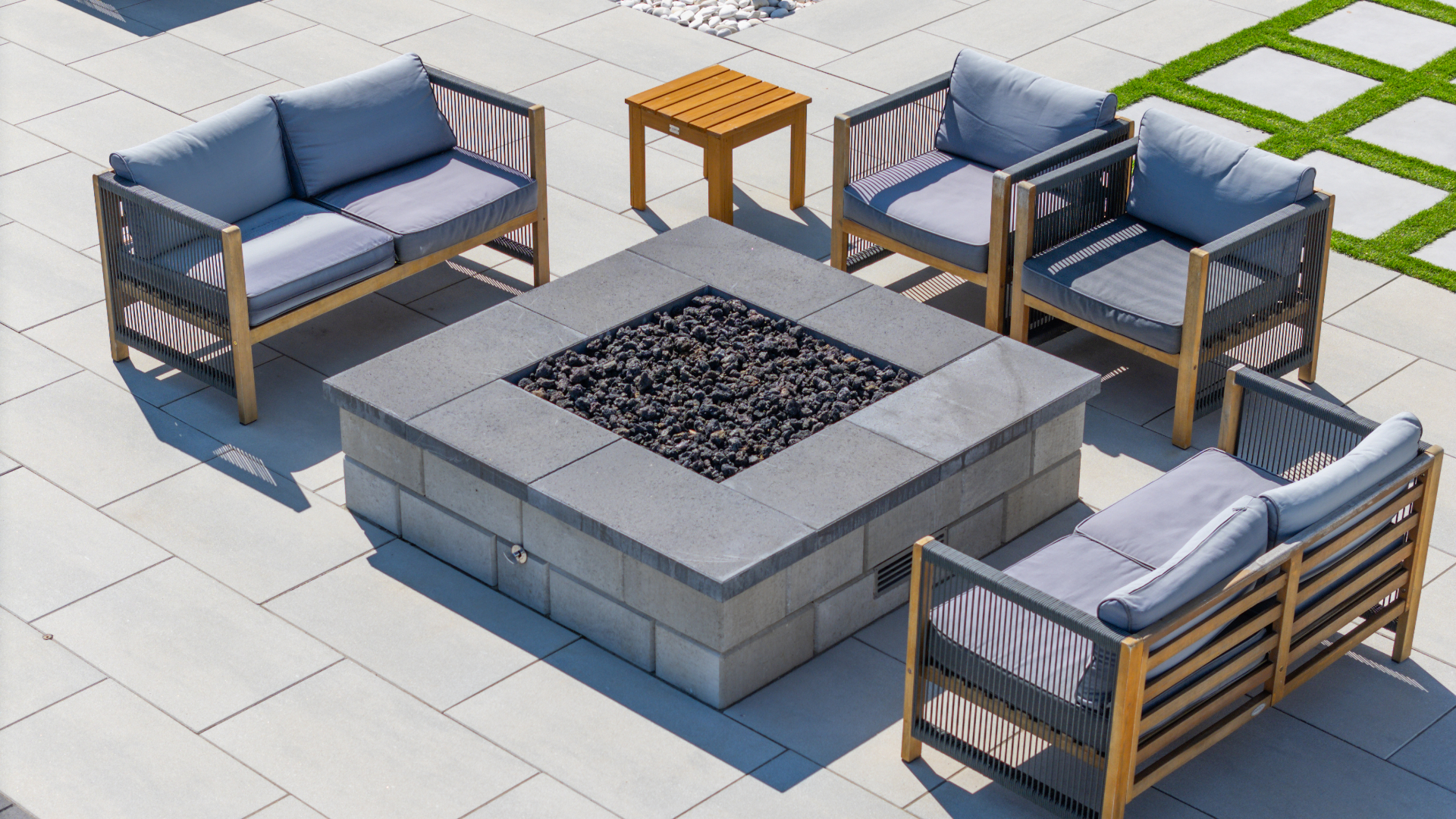 Aerial view of a stone fire feature and coordinated lounge seating within a finished patio zone.