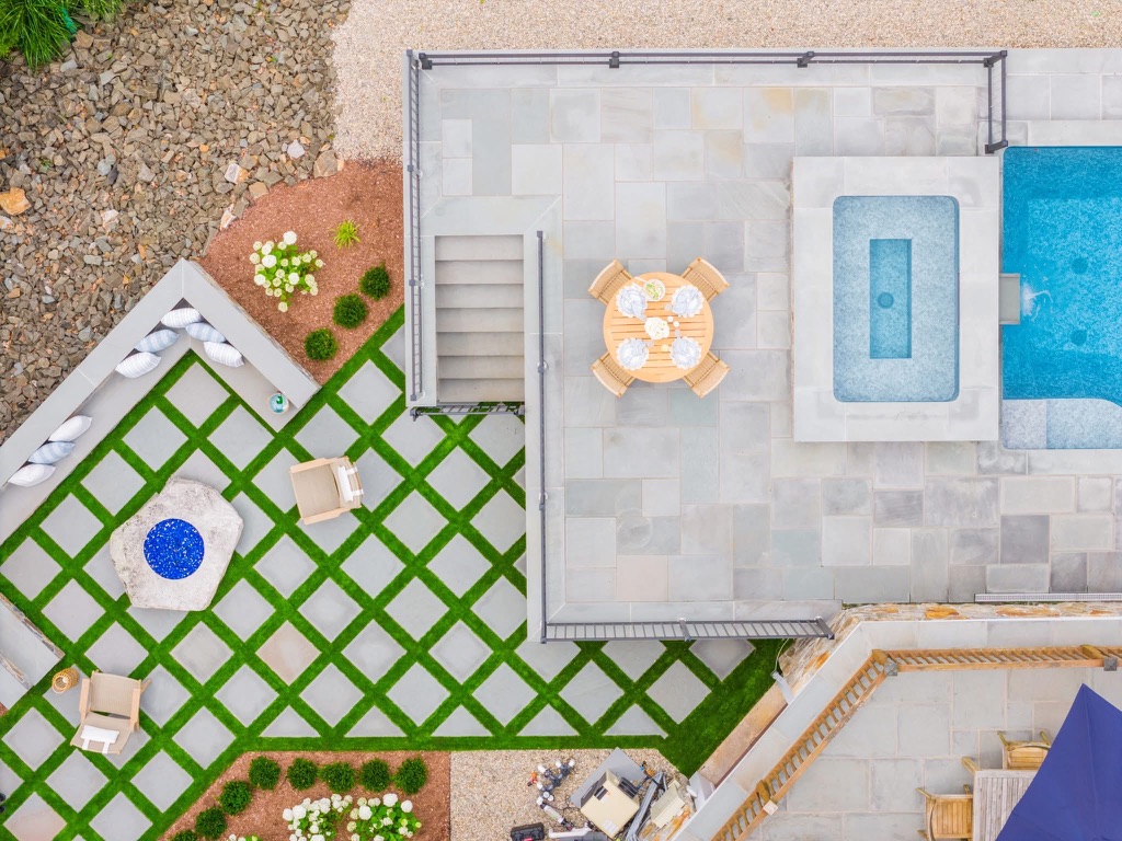 Overhead view of a bluestone terrace with grass joint checkerboard paving, fire pit, and dining area