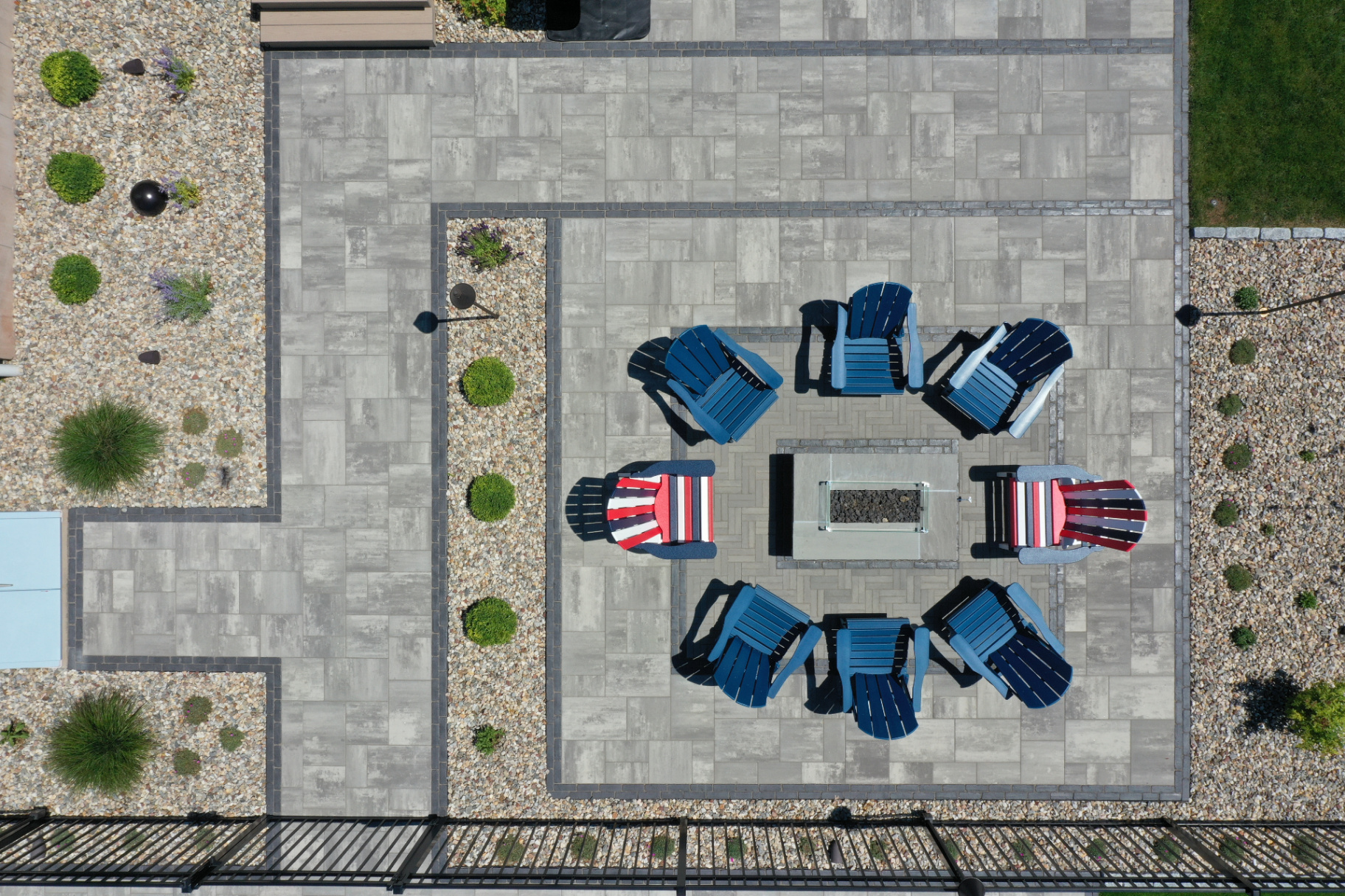 Aerial view of a paver patio with fire pit and Adirondack chairs, reading like a site plan.