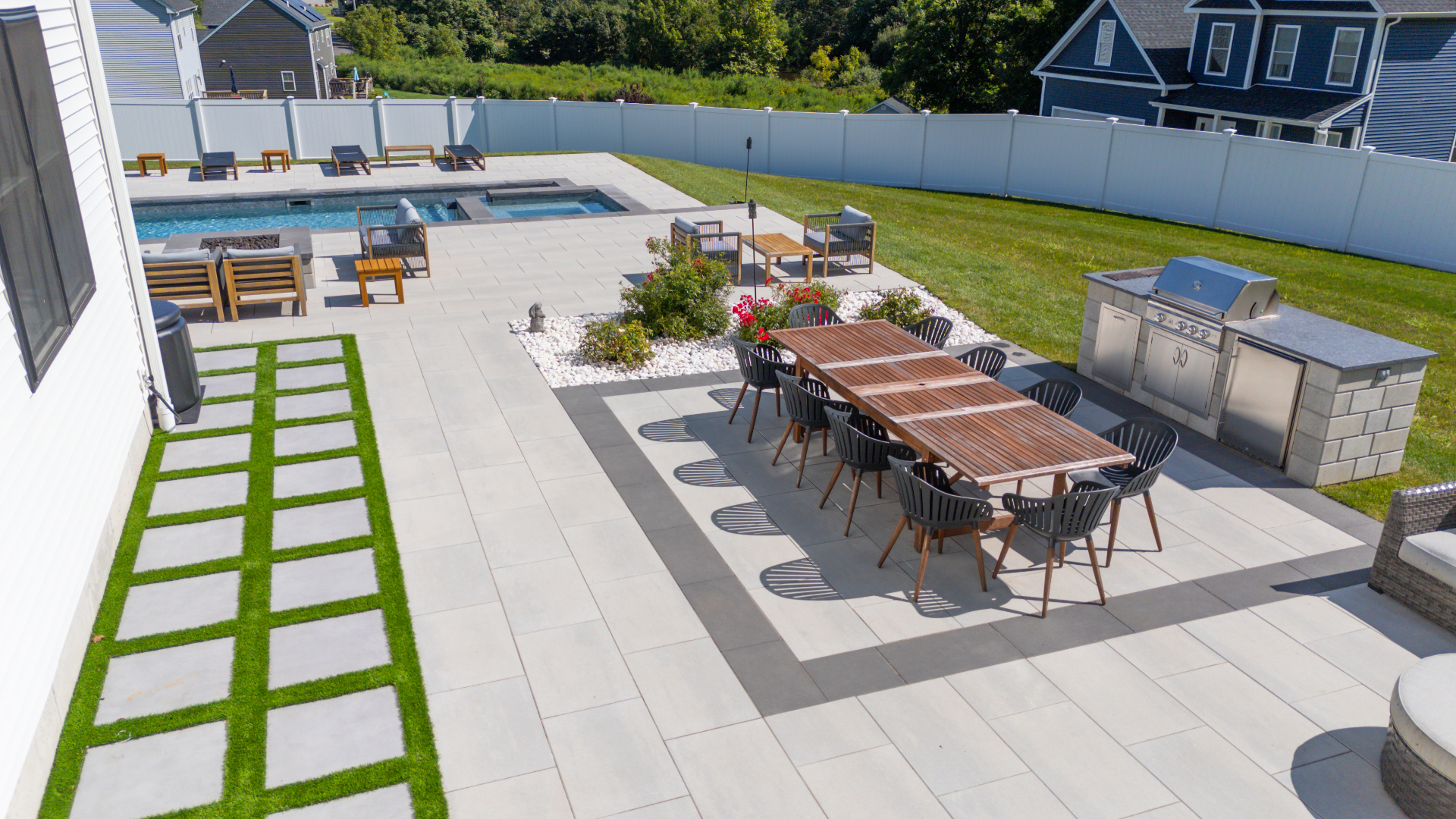 A full backyard with pool, spa, dining area, outdoor kitchen, and multiple landscaped zones